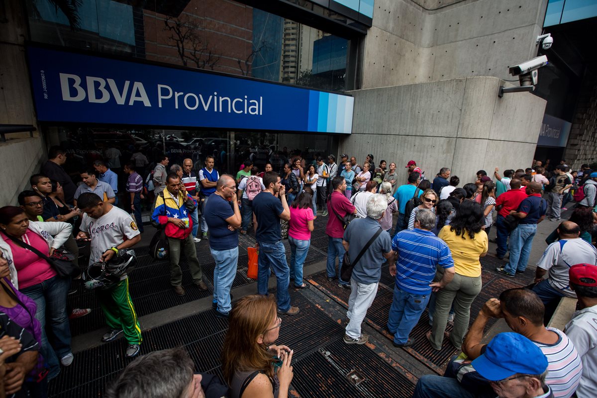 Cientos de personas esperan frente a un banco para cambiar billetes. (Foto PL: EFE)