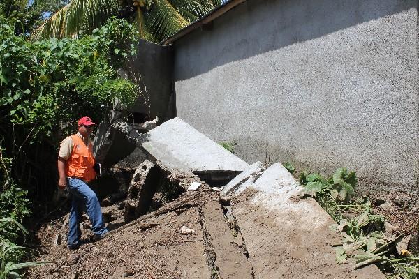 Funcionario de la Conred observa los daños en una vivienda,  causados por crecida de quebrada.