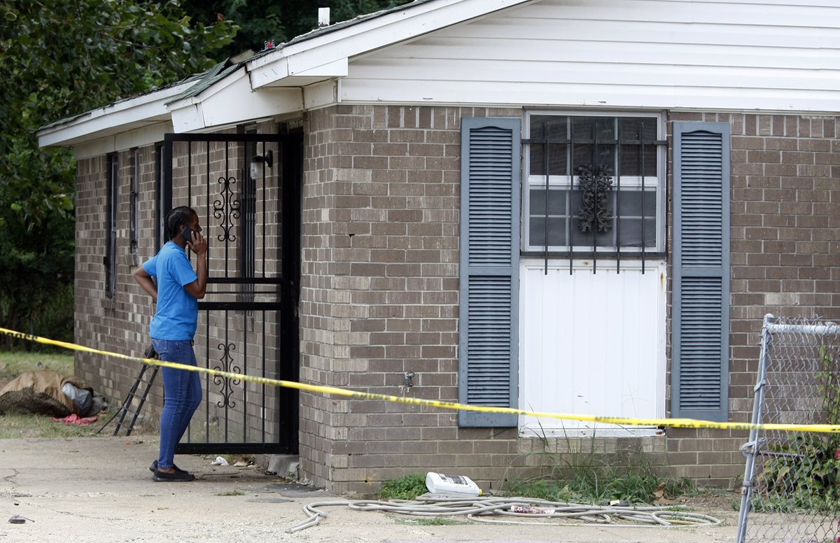 Una mujer observa la vivienda donde ocurrió la tragedia que acabó con varios integrantes de la familia. (Foto Prensa Libre: AP).