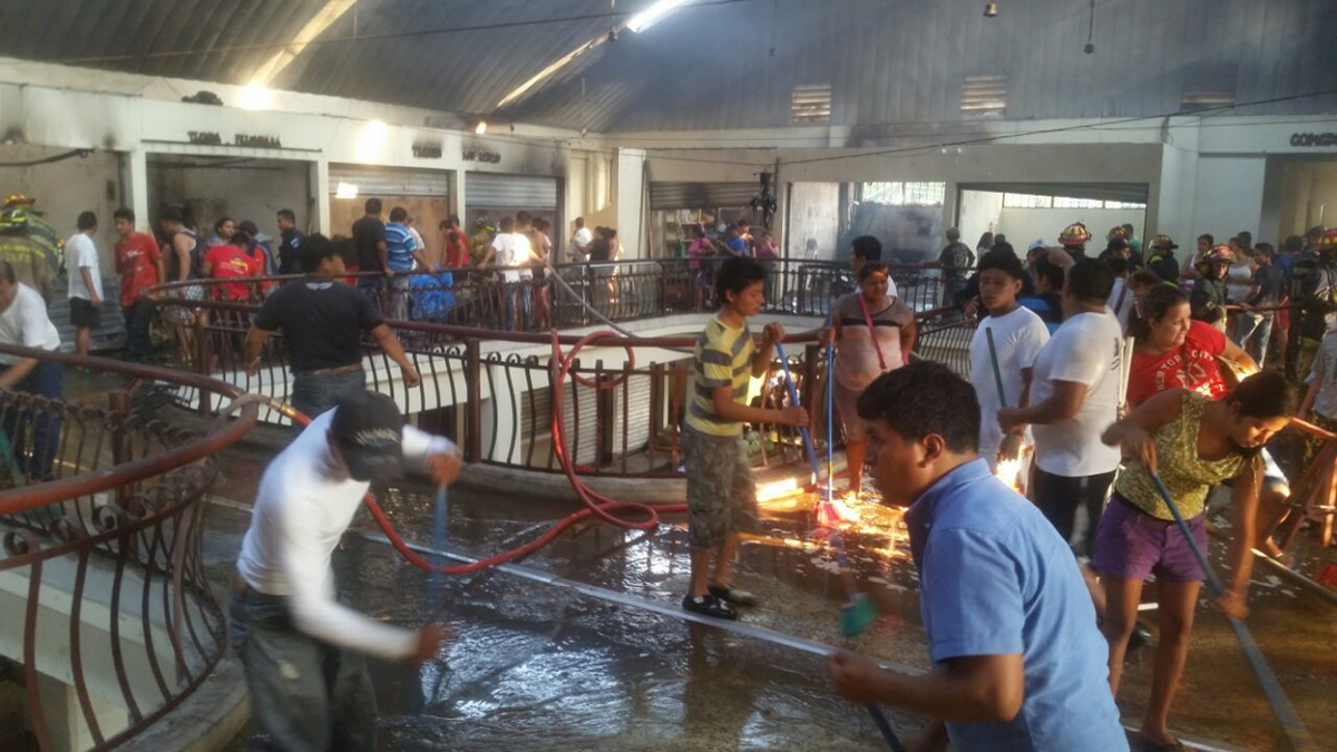 Vendedores limpian el área donde ocurrió el incendio. (Foto Prensa Libre: Cristian Icó Soto)