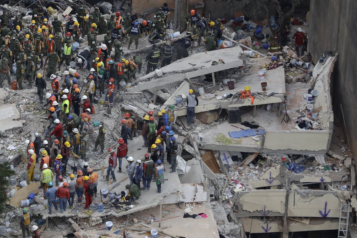 Recatistas buscan personas atrapadas dentro de un edificio colapsado en el área de Del Valle de la Ciudad de México. (AP).