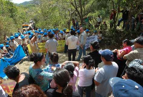 empleados de la mina, con cascos azules,  frente a los vecinos que bloquean el camino.