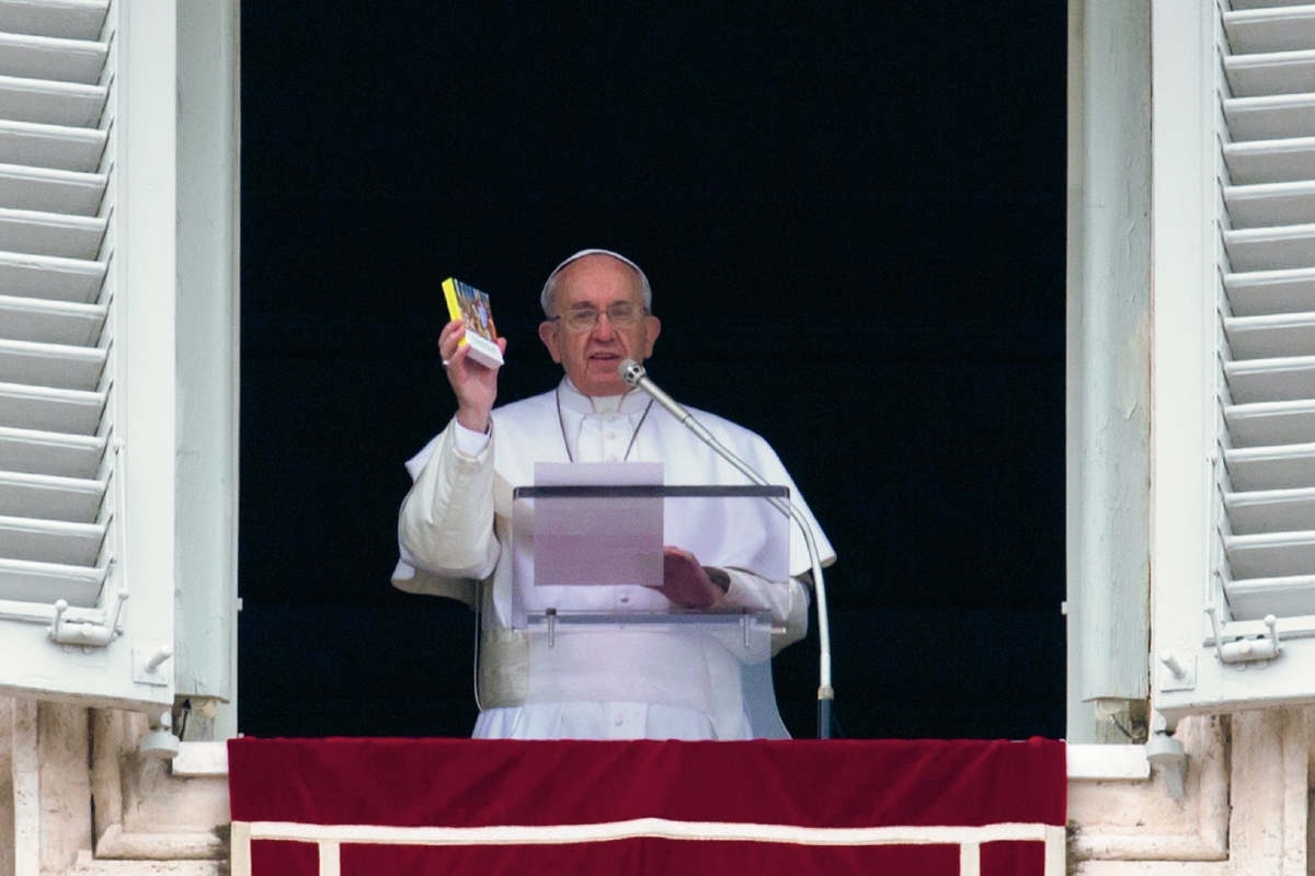 El papa Francisco sostiene una copia de bolsillo de los Evangelios durante el rezo del Ángelus en la Plaza de San Pedro . (Foto Prensa Libre:AP)