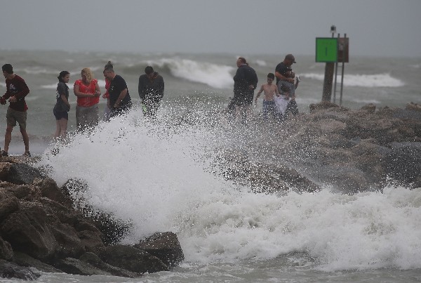 Varias personas disfrutan de las olas de la tormenta tropical Colin. (AFP).