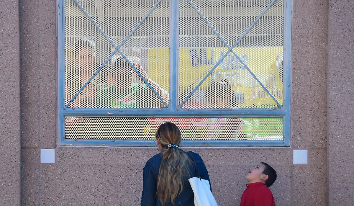 Una mujer y su hijo permanecen en el muro fronterizo en Nogales, México, límite con EE. UU. (Foto Prensa Libre: AFP).