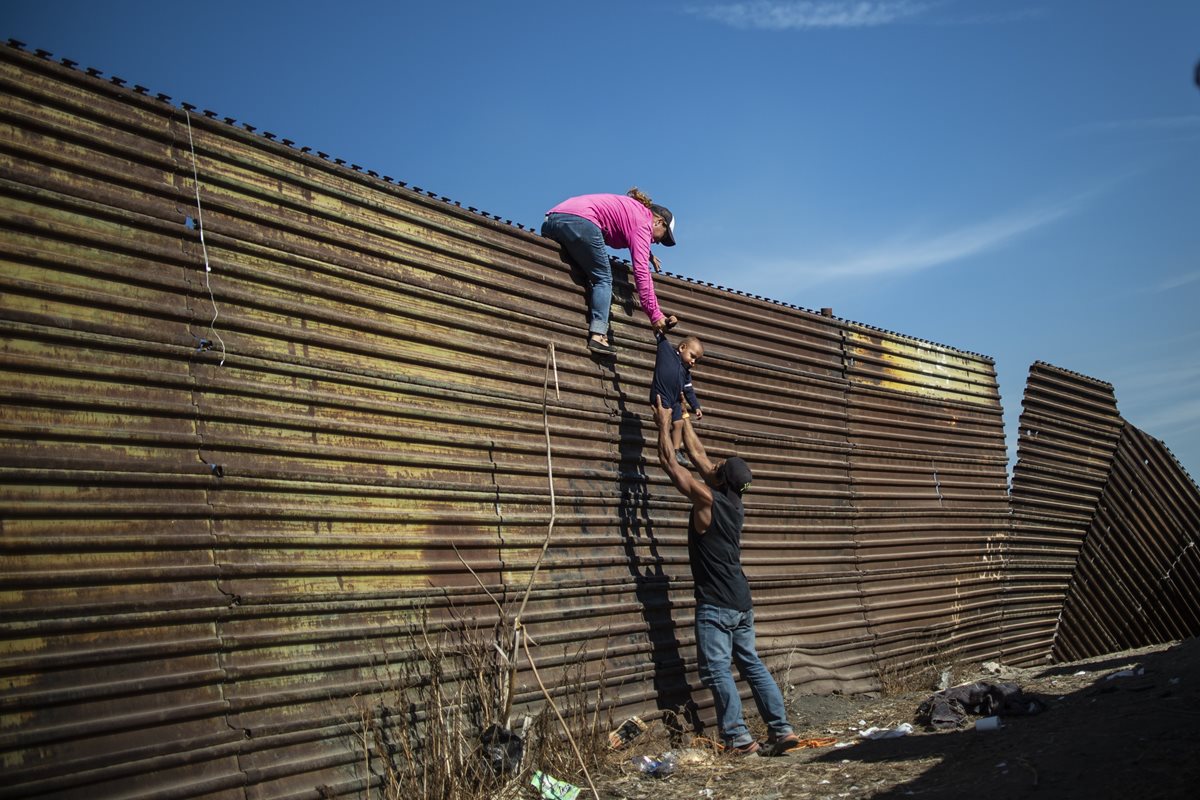 Migrantes intentan cruzar por valla fronteriza en Tijuana, México. (Foto Prensa Libre: AFP)