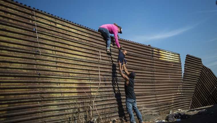 Migrantes intentan cruzar por valla fronteriza en Tijuana, México. (Foto Prensa Libre: AFP)