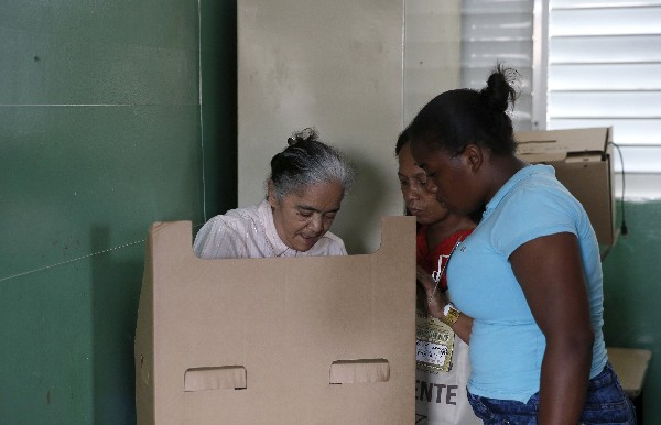 Una mujer acompañada de dos familiares vota en Santo Domingo.(EFE).