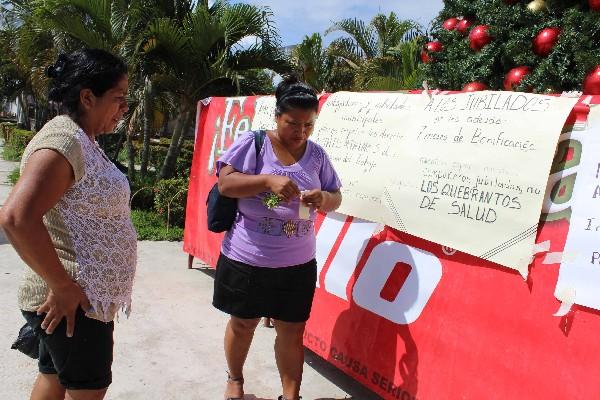 trabajadoras  municipales   pegan  carteles en los que  exigen los pagos atrasados.