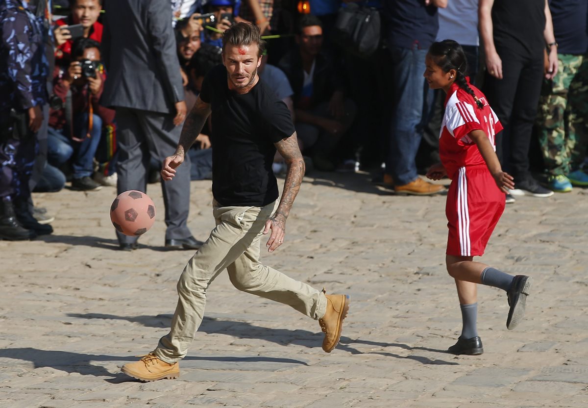 El exfutbolista inglés David Beckham juega al futbol con estudiantes nepalíes en la plaza de Bhaktapur Durbar en Bhaktapur. (Foto Prensa Libre: EFE)