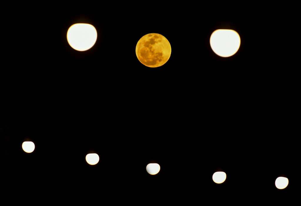 En la composición fotográfica se observa la luna llena, junto a luces de Navidad, en Panamá.