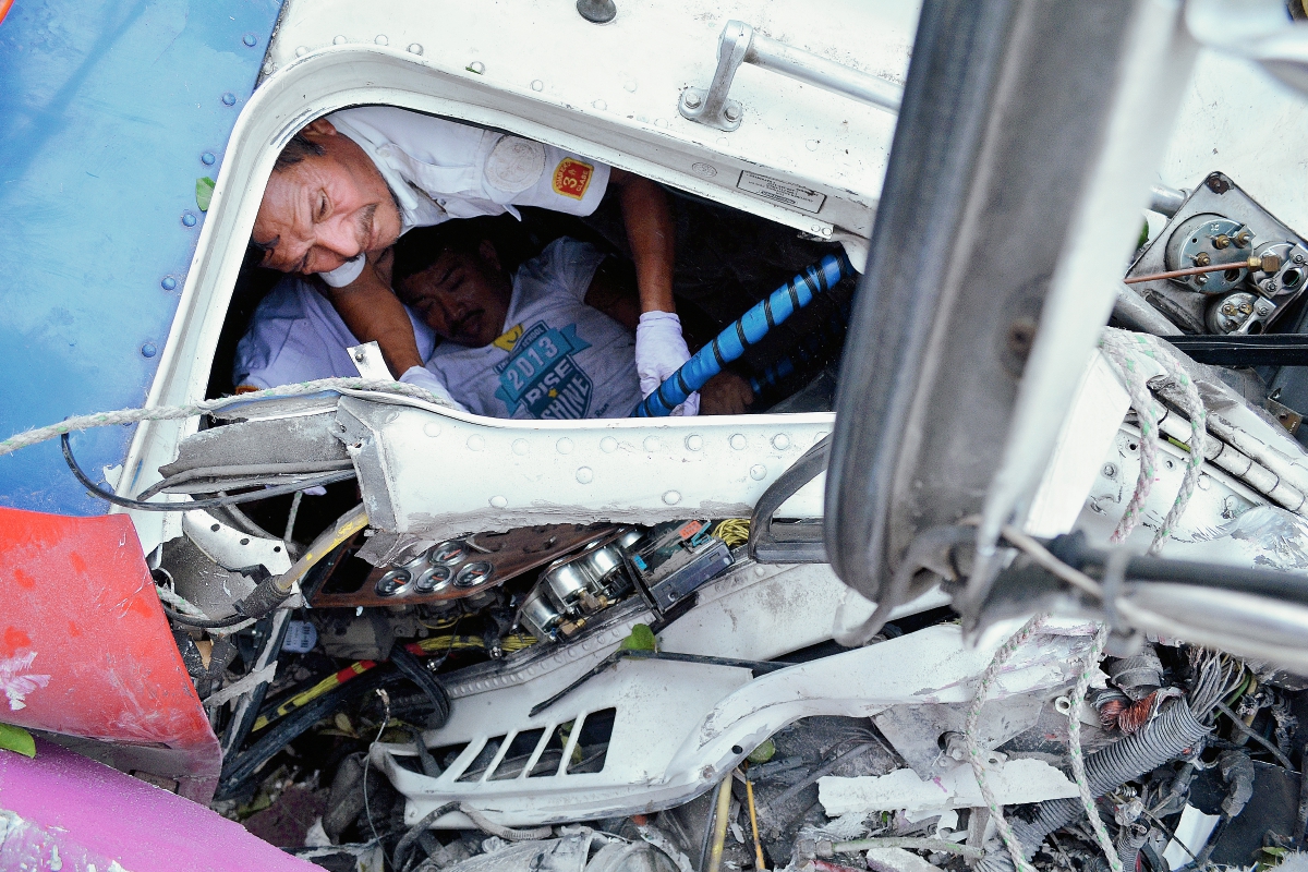 Un socorrista rescata al piloto del tráiler que se accidentó, en el km 197 de El Asintal, Retalhuleu. (Foto Prensa Libre: Jorge Tizol)