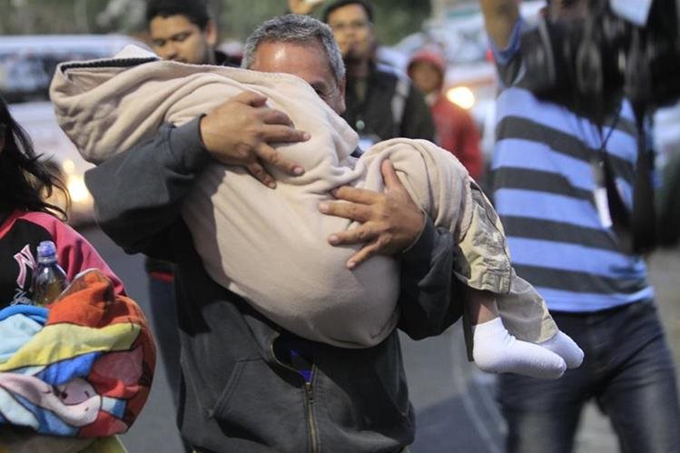 Un familiar lleva en sus brazos a uno de los menores que estaba bajo protección en el Hogar Seguro, el día de la tragedia. (Foto Prensa Libre: Hemeroteca PL)