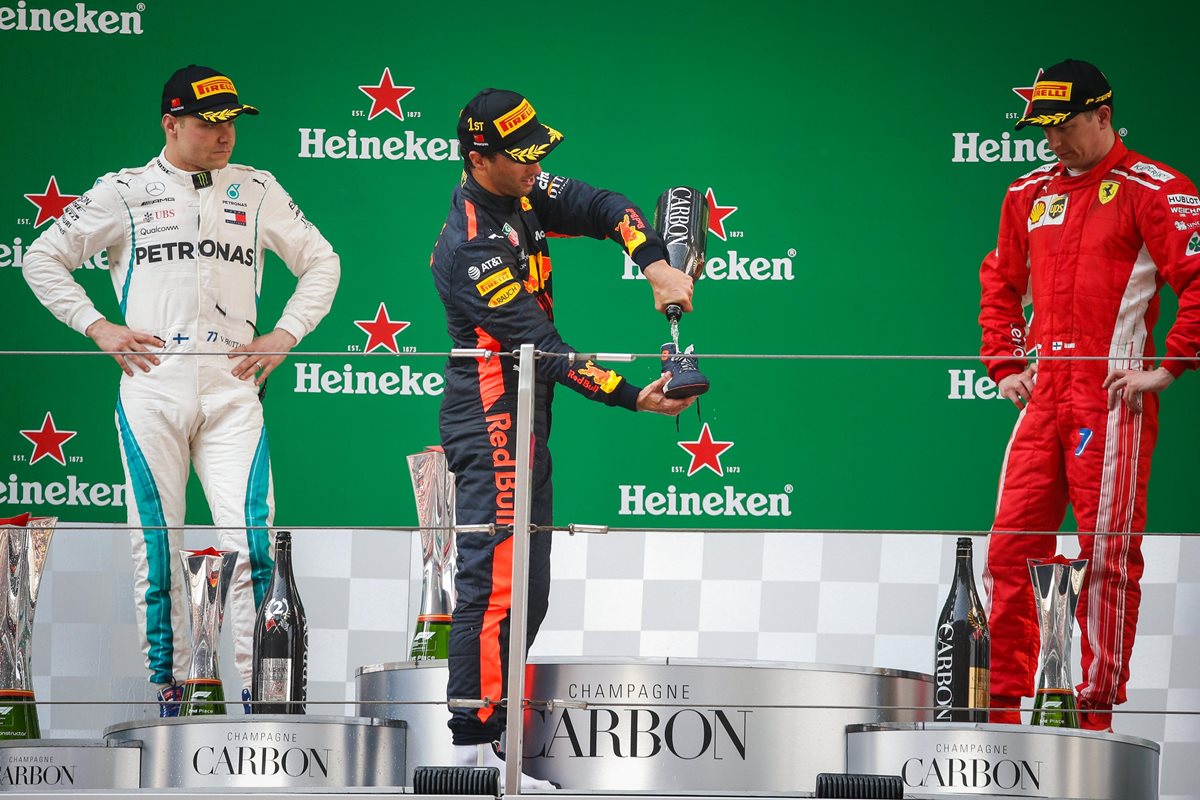 Ricciardo se sirve champán en su zapato mientras es observado por Valtteri Bottas y  Kimi Raikkonen. (Foto Prensa Libre: EFE)