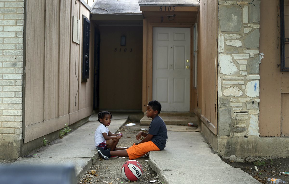 Niños juegan frente a la vivienda donde las autoridades encontraron a ocho niños, dos de ellos atados en el patio de la casa en Texas. (Foto Prensa Libre: AP).