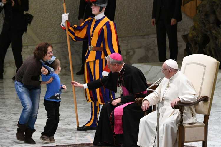 Una mujer sostiene a su hijo luego de que el pequeño de siete años corriera a saludar al papa.
