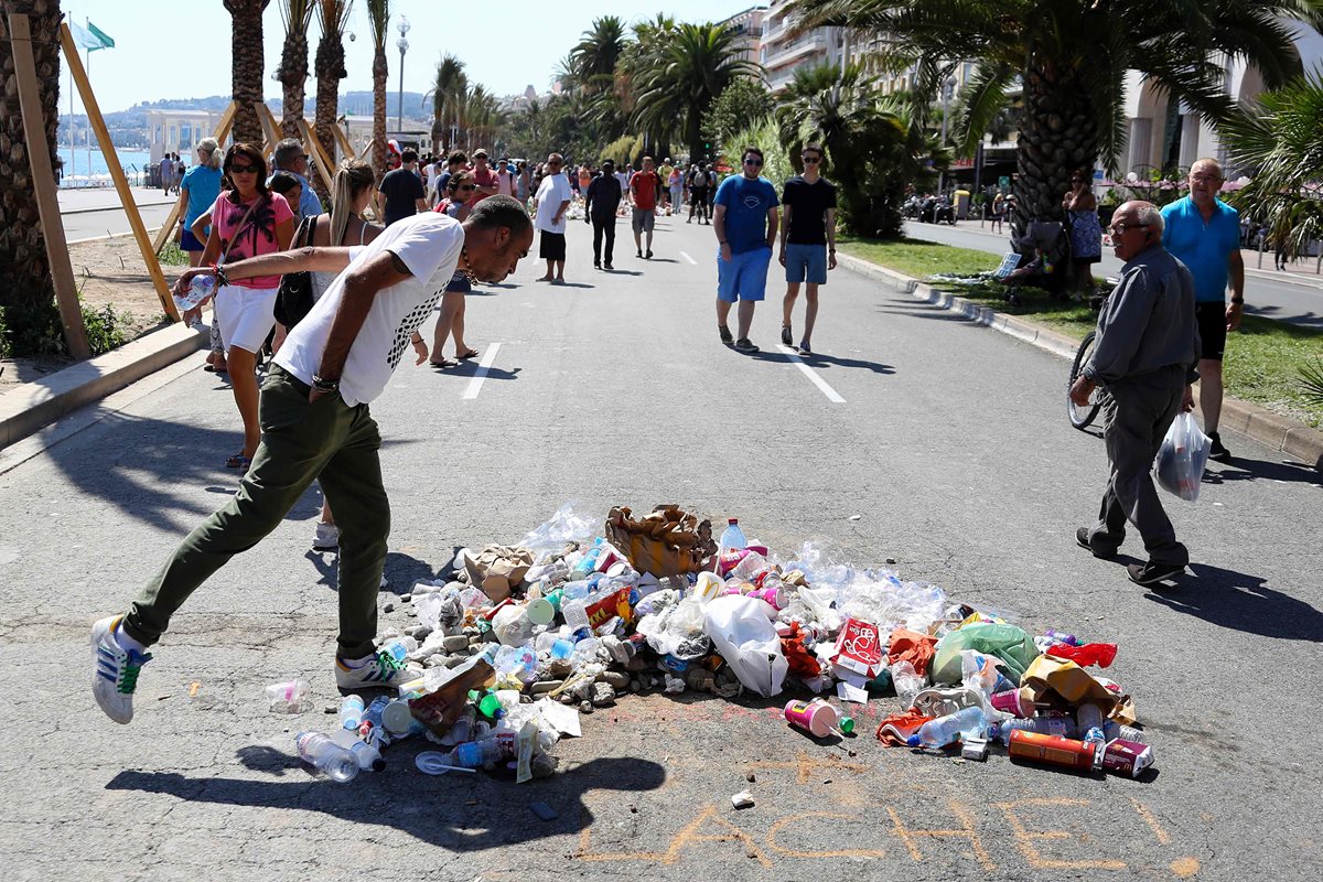 Un hombre escupe en el lugar donde Mohamed Lahouaiej Bouhlel cayo muerto, abatido por la Policía en Niza. En el área las personas han lanzado basura y escrito la frase "¡cobarde!". (Foto Prensa Libre: AFP).