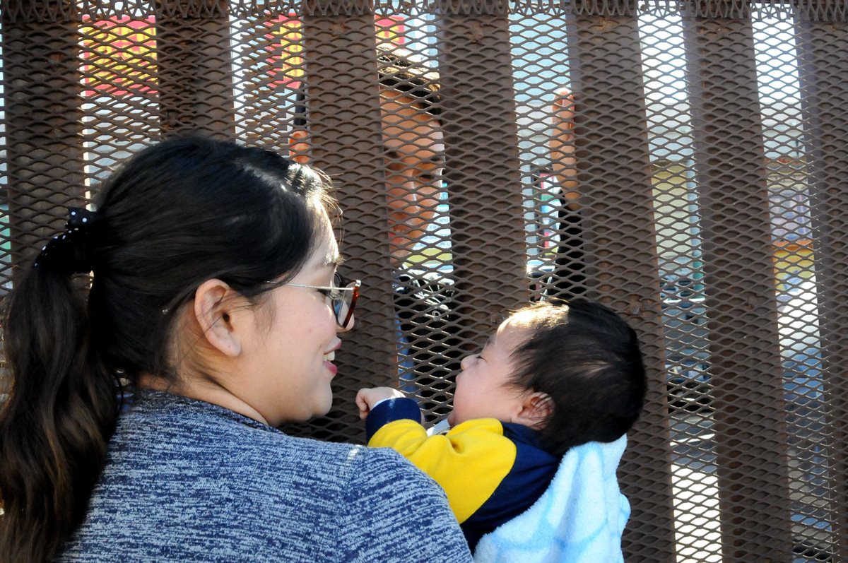 Samanta, en EE. UU. y Marco (atrás) en México, con un muro de por medio, se saluda en la frontera de Calexico. (Foto Prensa Libre: EFE).