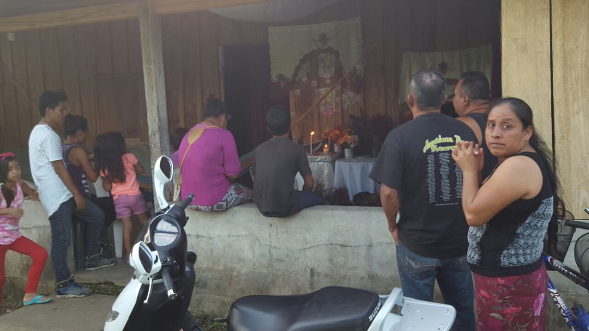 Vecinos de Poptún se reúnen en una vivienda donde una mujer asegura que en una pared de madera apareció una imagen religiosa. (Foto Prensa Libre: Walfredo Obando) 