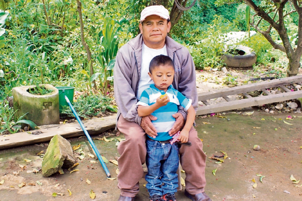 Lorenzo Pablo Jeteyá, junto a uno de sus hijos, en el patio de su casa, en San José Chacayá, Sololá.