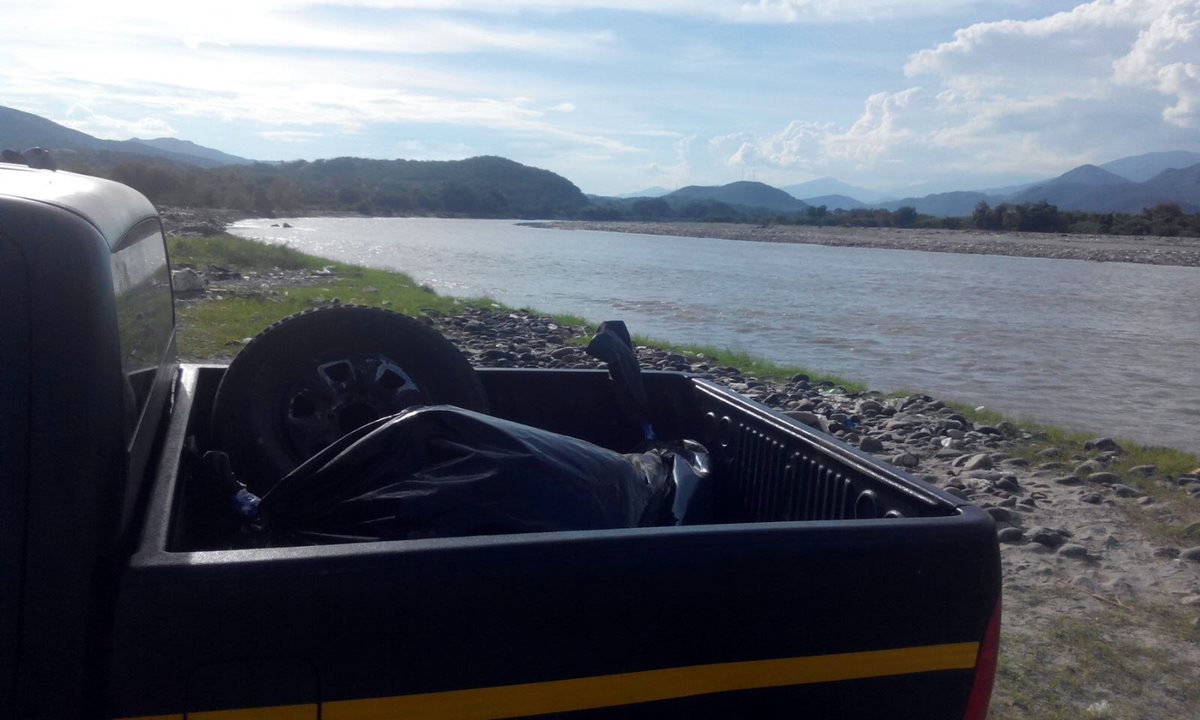 Agentes de la PNC colocan en la palaganda de su vehículo el cádaver que fue localizado en el río Motagua. (Foto Prensa Libre: Hugo Oliva)