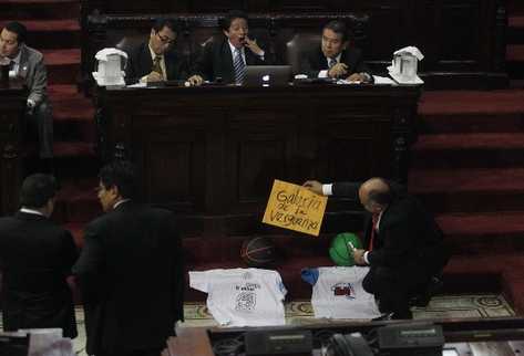 El ministro de Cultura, Carlos Batzín, bosteza mientras  el diputado de Líder, Luis Chávez, coloca balones y vestuario frente al interpelado.