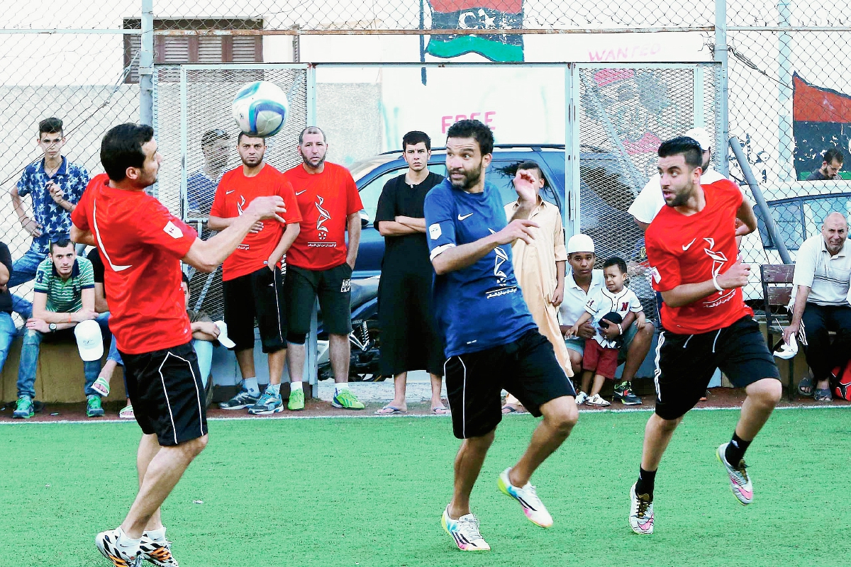 Jóvenes libios tratan de olvidarse de las penas que significa vivir en medio de una guerra civil mientras juegan un partido de futbol en Trípoli. (Foto Prensa Libre: AFP).