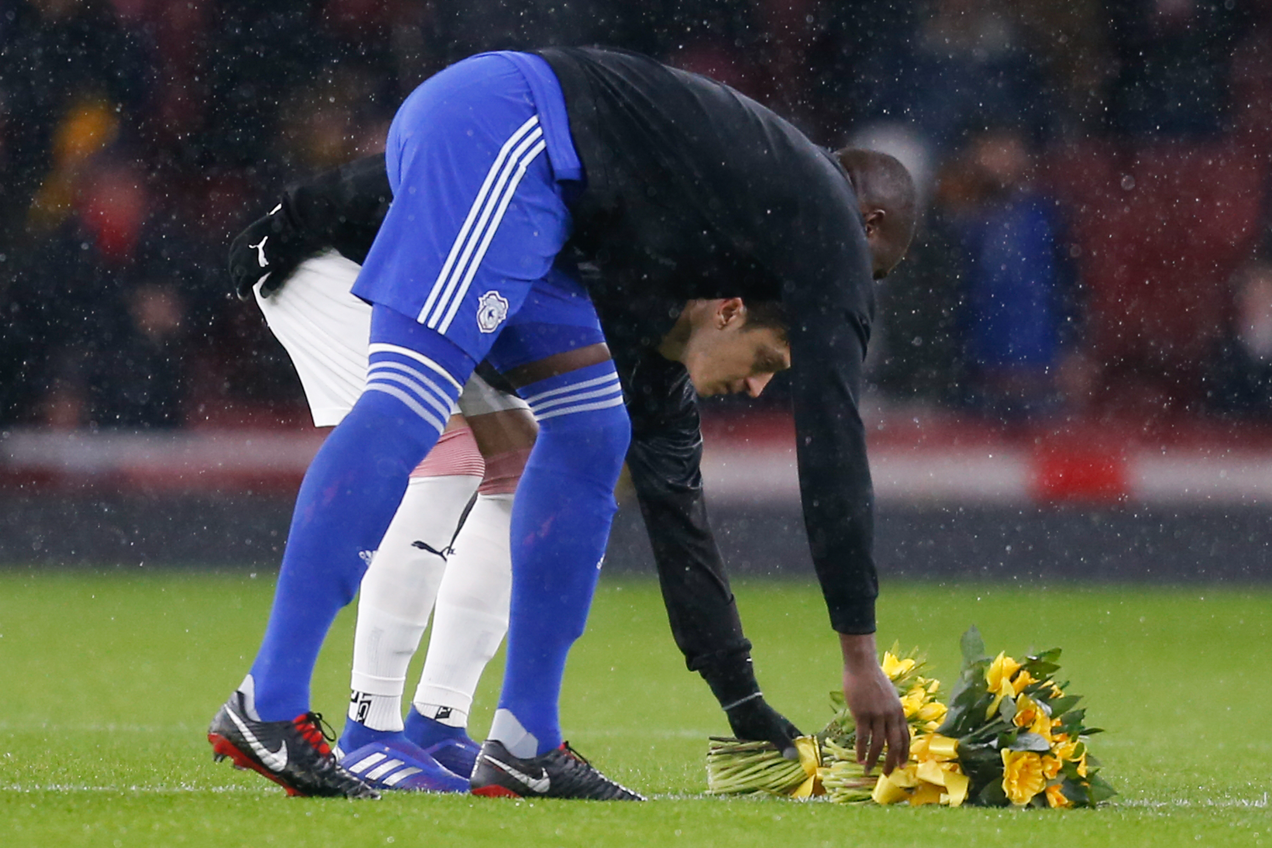El capitán del Arsenal Mesut Ozil y el del Cardiff Sol Bamba colocan una ofrenda floral en el centro del campo en honor al argentino Emiliano Sala. (Foto Prensa Libre: AFP)