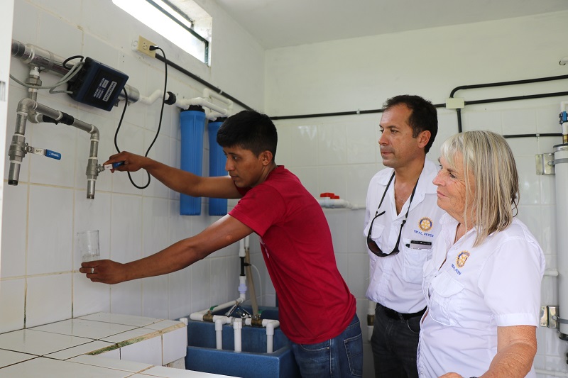 Representantes del Club Rotario observan mientras un líder de Carmelita recibe líquido purificado del sistema instalado en esa comunidad. (Foto Prensa Libre: Rigoberto Escobar)