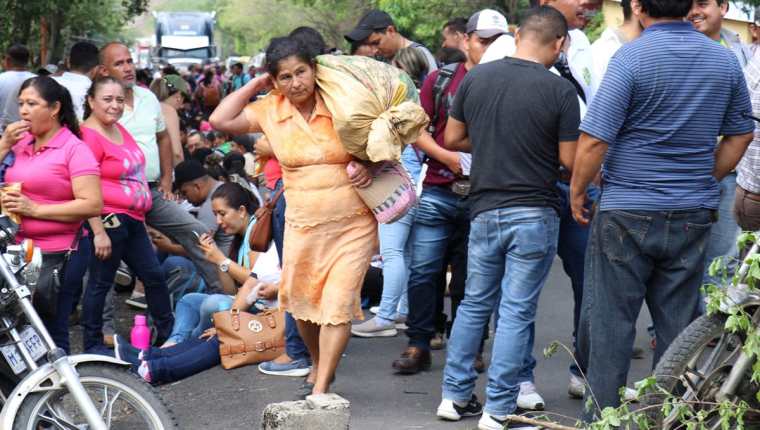 Una mujer afectada por los bloqueos carga con sus pertenencias para sortear la protesta en el km 176 de cruce a Vado Hondo, Chiquimula, y camina en medio de los maestros. (Foto Prensa Libre: Mario Morales)