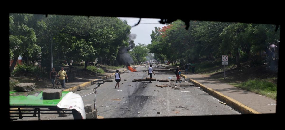 Varias personas son vistas a través de una ventana de un autobús incendiado por manifestantes en Tipitapa, a unos 25 km de Managua. (AFP).