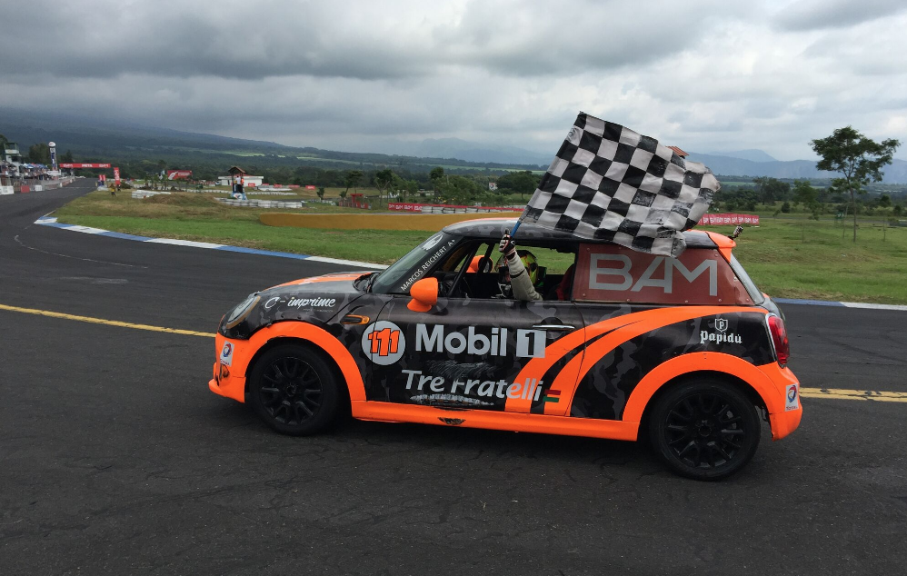 Marcos Reichert conduce su vehículo con la bandera a cuadros luego de coronarse campeón de la Copa Mini. (Foto Prensa Libre: Autódromo Pedro Cofiño)