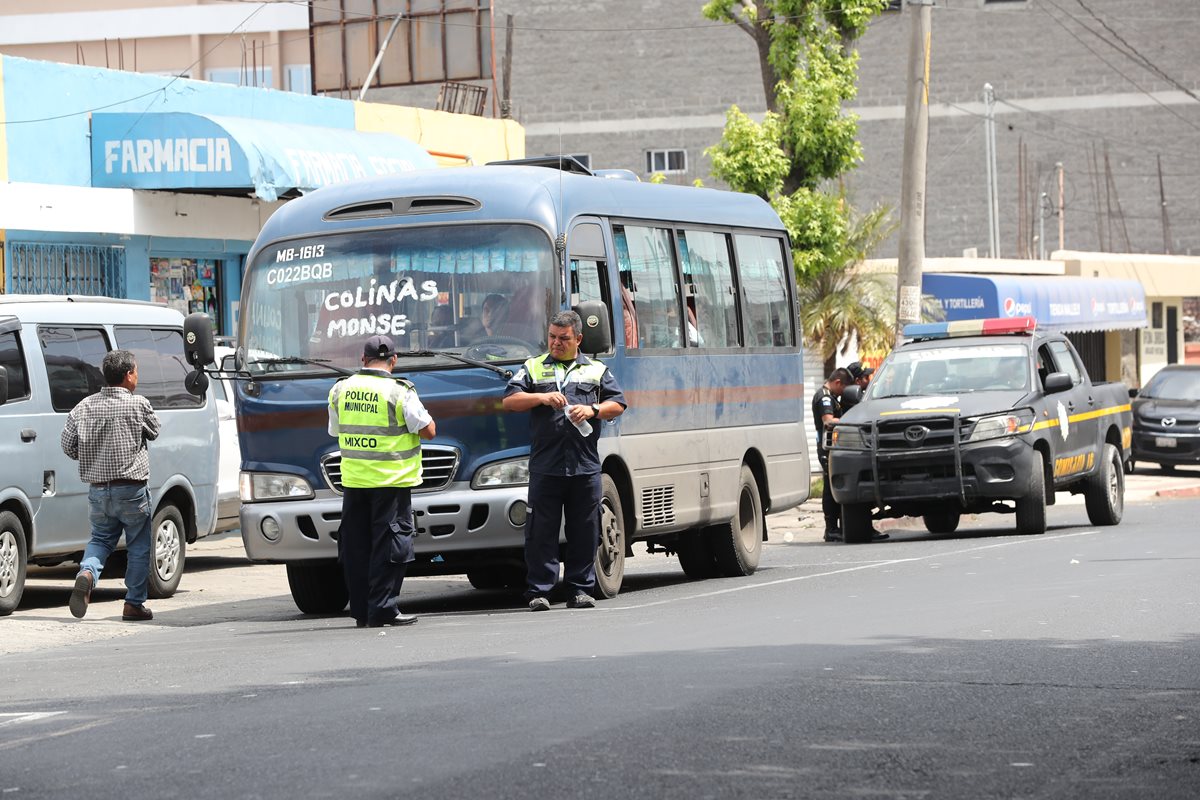 Un policía Municipal custodia un microbús en la estación de la 40 avenida y calzada San Juan, zona 4 de Mixco. (Foto Prensa Libre: Érick Ávila)