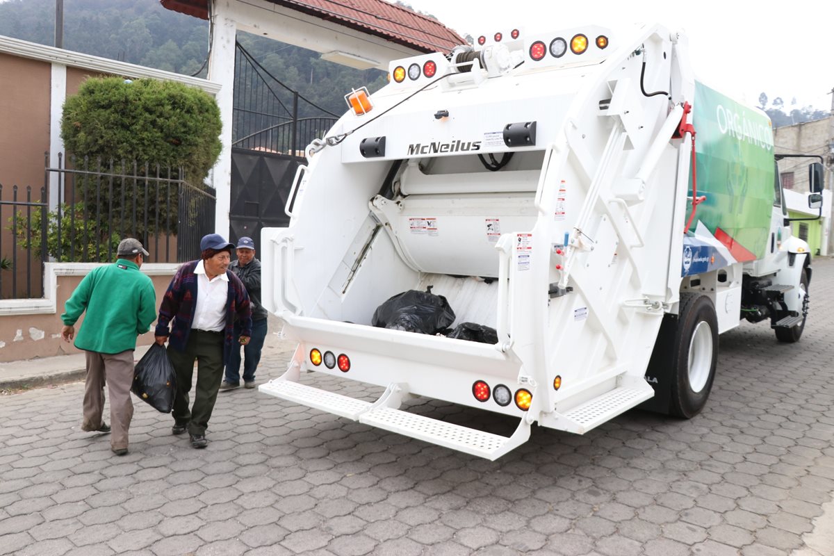 Residente de Xela y trabajadores de la comuna llevan las bolsas de basura orgánica al camión que compró la municipalidad. (Foto Prensa Libre: María José Longo).