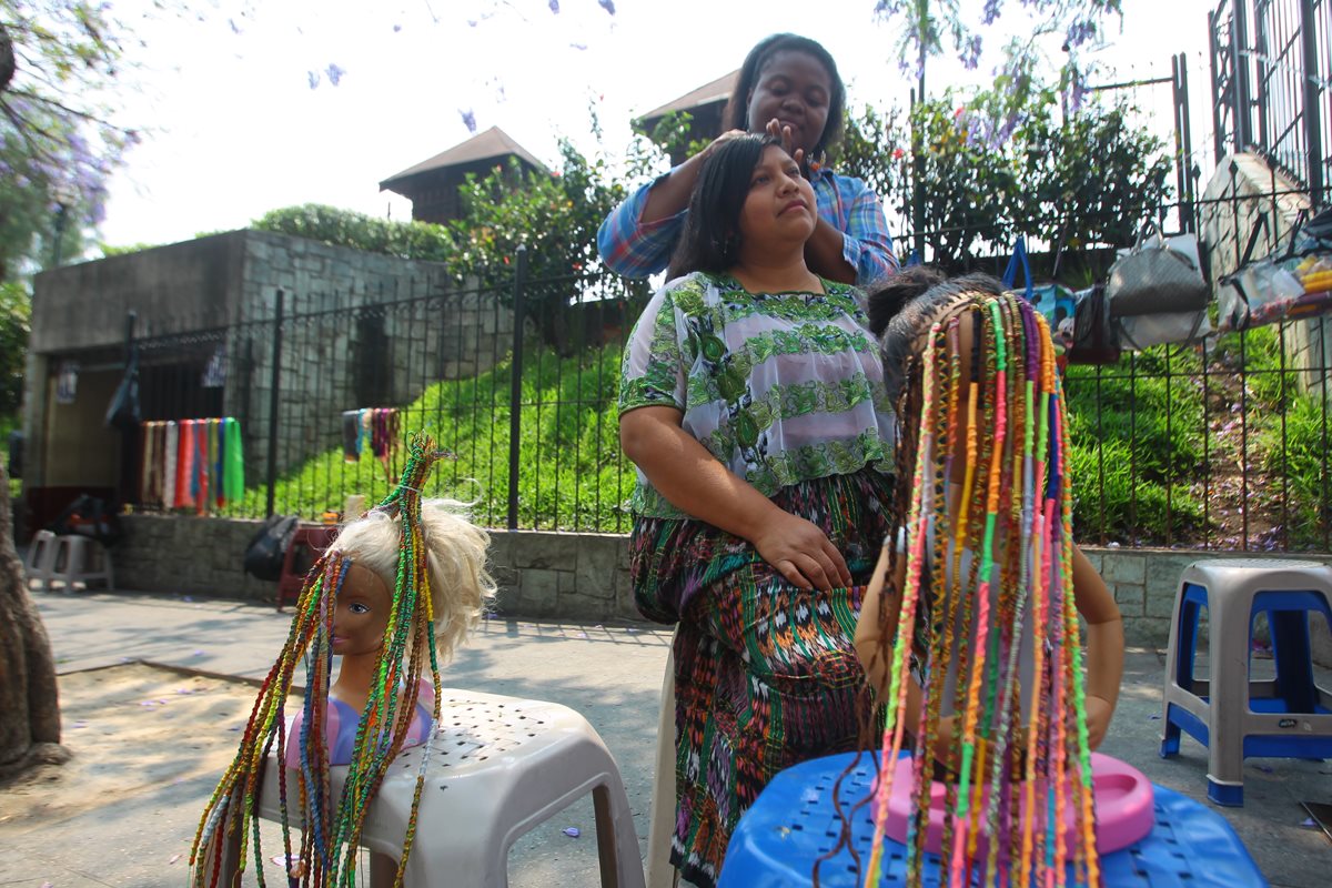 Una de las mujeres procedentes de Izabal elabora trenzas en el cabello de una joven. (Foto Prensa Libre: Álvaro Interiano).