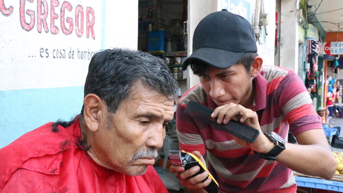 Rolando Fernández corta el cabello a Julio Jiménez, en Mazatenango. (Foto Prensa Libre: Cristian I. Soto)