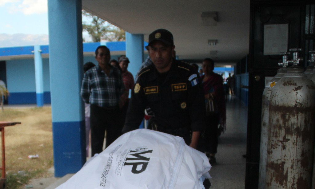 Agente de la PNC traslada el cadáver de Sherlyn Beraly Lajuj Ramos a la morgue de Huehuetenango. (Foto Prensa Libre: Mike Castillo).