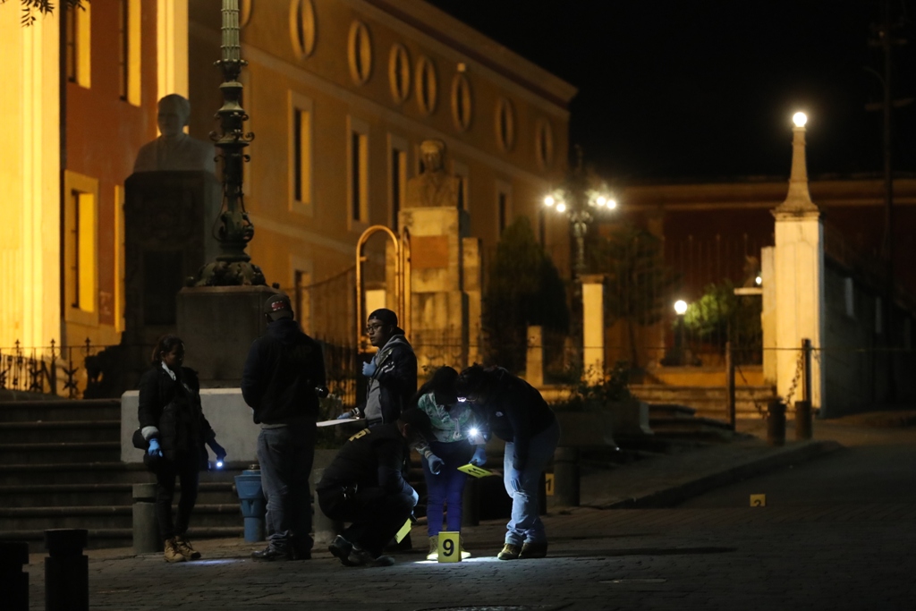 Investigadores del Ministerio Público revisan el área donde la noche del sábado un hombre de 20 años fue ultimado a balazos frente al Teatro Municipal. (Foto Prensa Libre: Mynor Toc)  