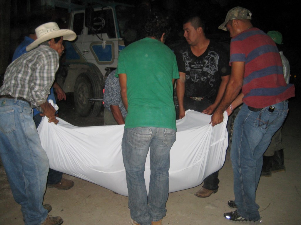 Familiares cargan cadáver baleado de propietario de hotel en Sayaxché, Petén. (Foto Prensa Libre: Rigoberto Escobar)