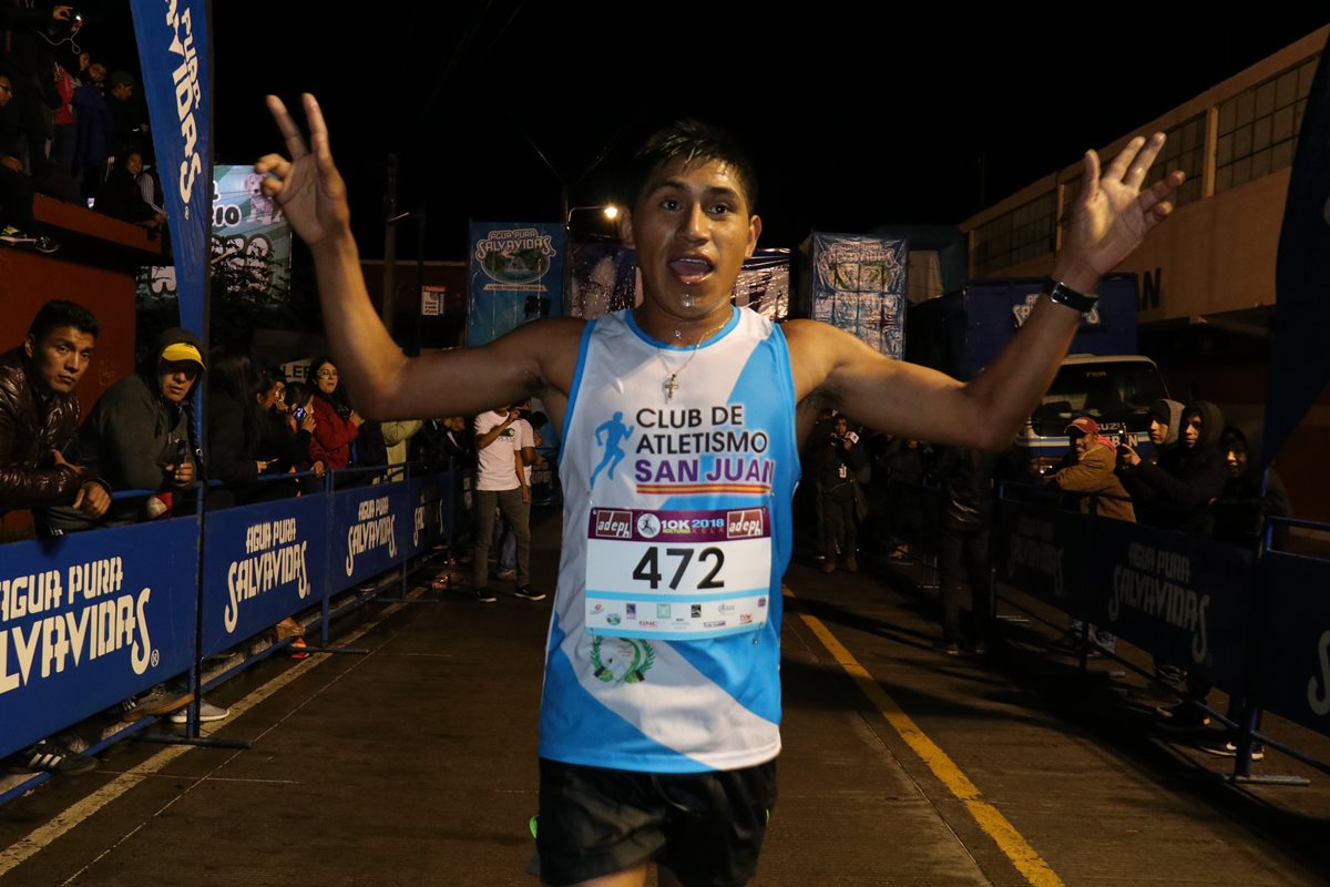 Carlos Ávila Raxón alza los brazos al cruzar la meta en los 10K nocturnos de Quetzaltenango. (Foto Prensa Libre: Raúl Juárez)