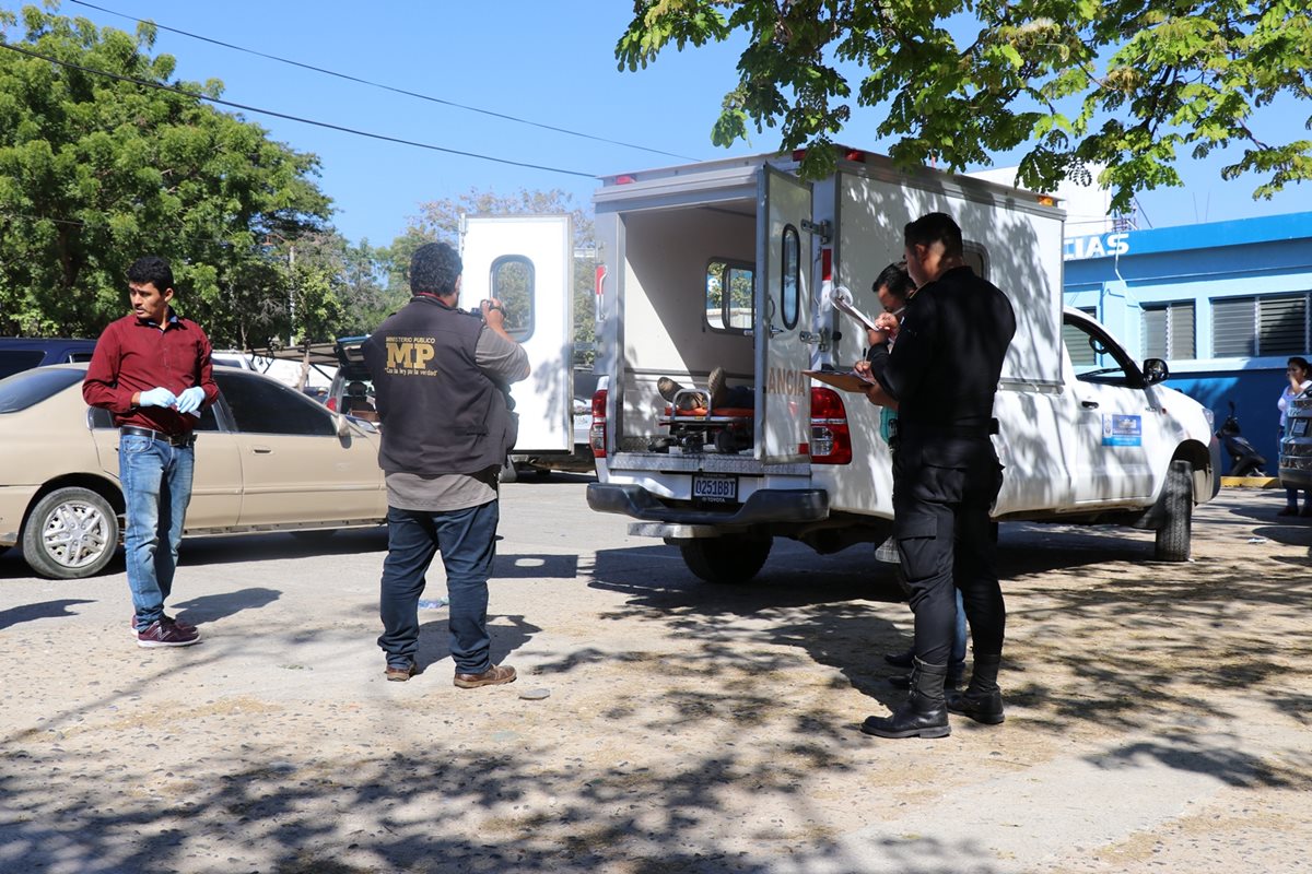 Fiscales del MP y agentes de la PNC resguardan la ambulancia donde murió el trabajador municipal. (Foto Prensa Libre: Mario Morales)