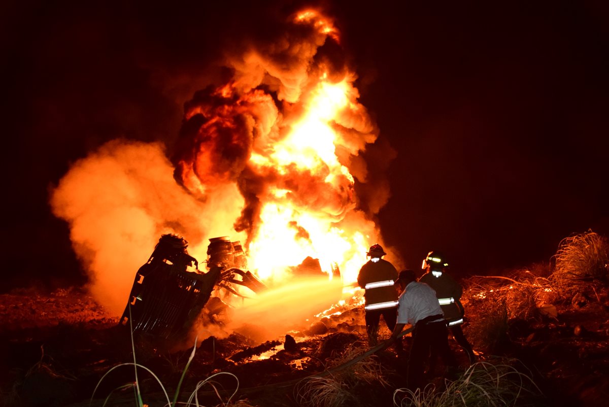 Personas observan a la orilla de la carretera mientras las llamas consumen al camión cisterna. (Foto Prensa Libre: Enrique Paredes)