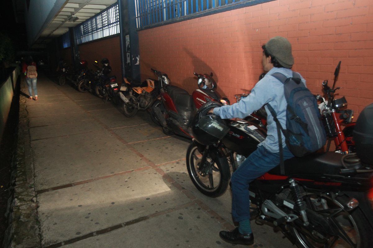 Un estudiante transita con su motocicleta en un área de la Usac donde hay escasa iluminación. (Foto Prensa Libre. Estuardo Paredes)