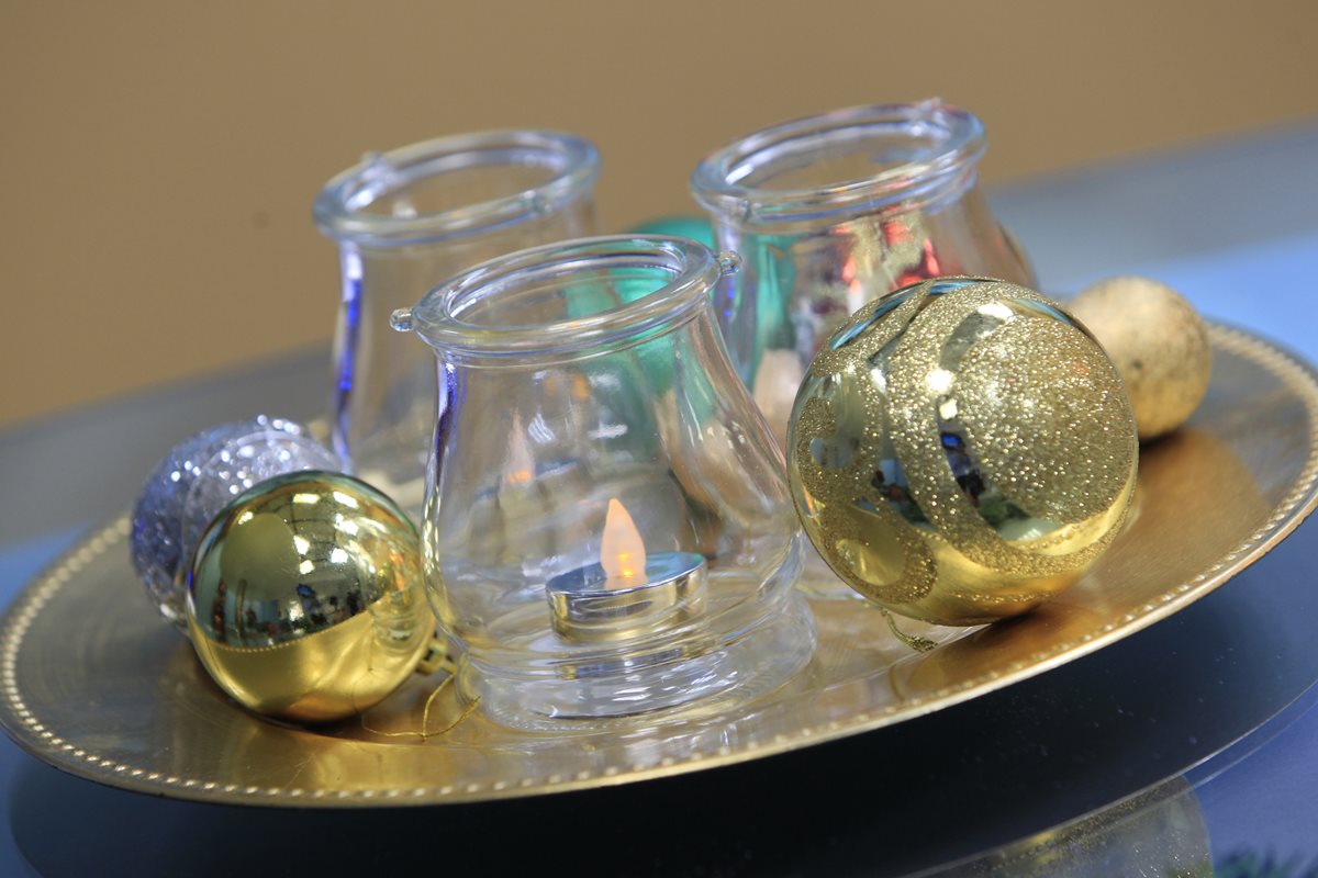 El dorado y el plateado son colores que siempre han caracterizado la decoración navideña. Este centro de mesa —sobre una base color oro— incluye bombas y vasos de cristal con velas con luz artificial en el interior. (Foto Prensa Libre: Carlos Hernández)