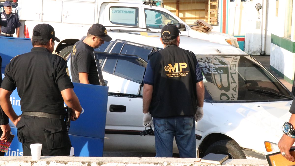 Fiscales del Ministerio Público revisan el taxi que transportaba a la comerciante muerta. (Foto Prensa Libre: Cristian Soto)