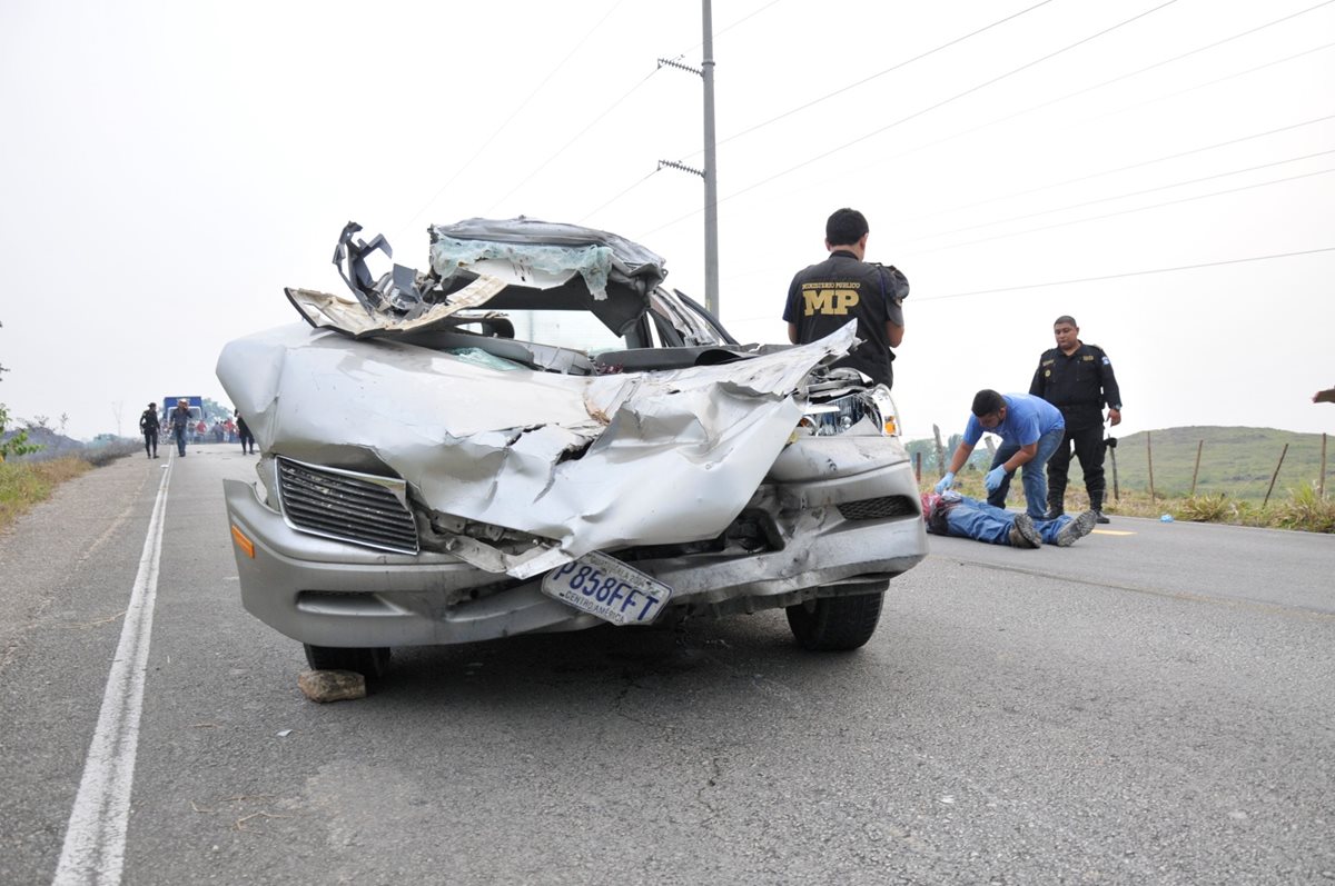 Vehículo en que se conducía Lusbin Asdrubal Galdámez Choc, de 40 años. Al lado, agentes del MP examinan cadáver. (Foto Prensa Libre: Rigoberto Escobar)