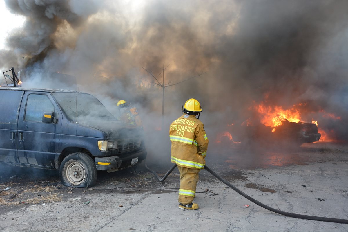 Bombero sofoca las llamas del incendio que causó daños en un predio de la PNC. (Foto Prensa Libre: Carlos Enrique Paredes)