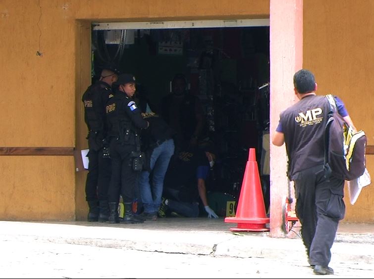 Fiscales del MP y agentes policiales trabajan dentro de la librería donde fue ultimado el líder campesino. (Foto Prensa Libre: Hugo Oliva)
