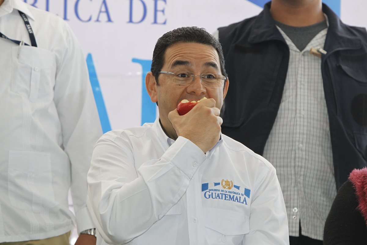 Jimmy Morales degusta la manzana que le regalaron vendedores de La Terminal. (Foto Prensa Libre: Paulo Raquec)