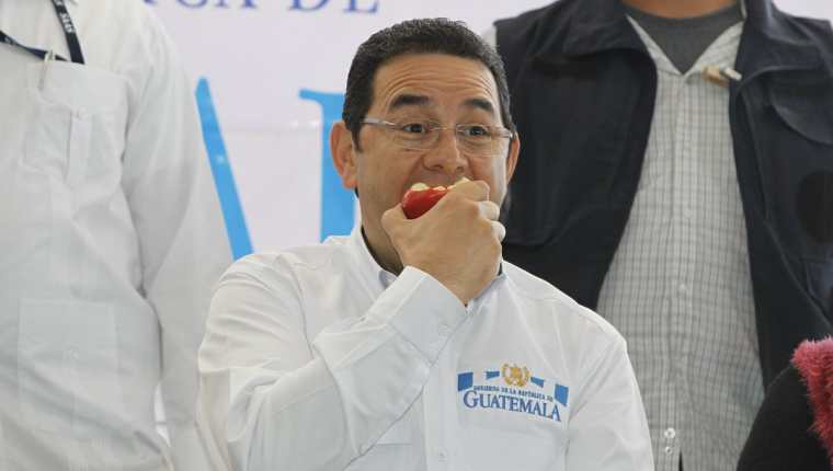 Jimmy Morales degusta la manzana que le regalaron vendedores de La Terminal. (Foto Prensa Libre: Paulo Raquec)